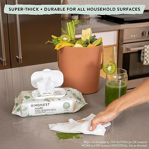 Compostable cleaning wipes with a kitchen compost bin and green smoothie.