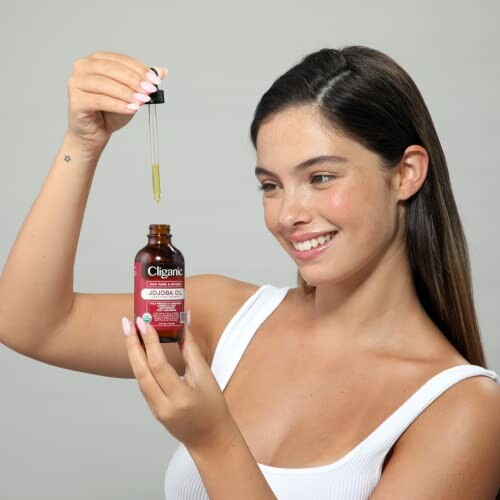 Woman holding a dropper with jojoba oil bottle