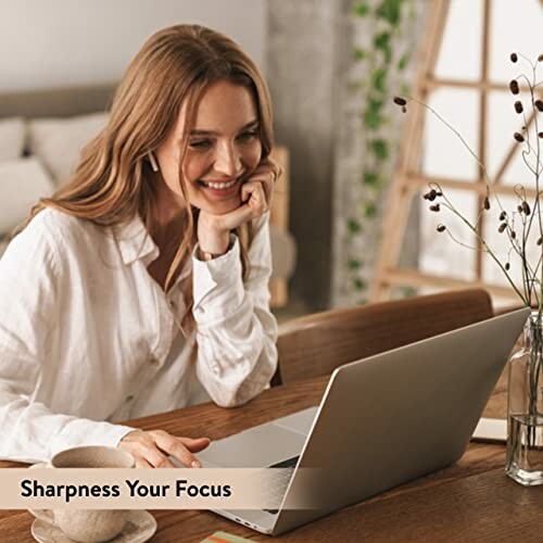 Woman smiling while working on a laptop at home.